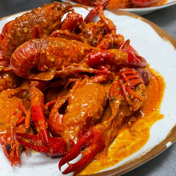 King Cajun Crawfish's vibrant red crawfish, generously coated in a rich, spicy orange sauce on a white plate.