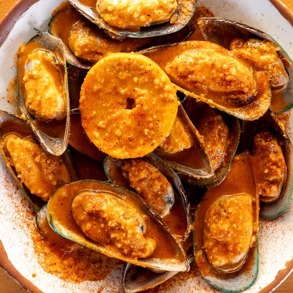 King Cajun Crawfish mussels in a rich, spicy orange sauce with a slice of citrus.