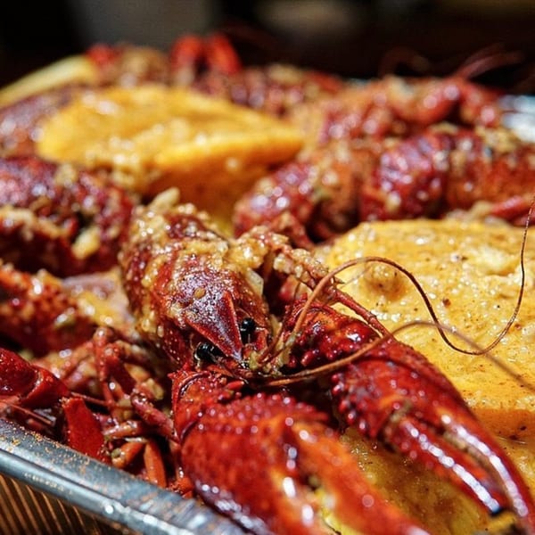 Close-up of King Cajun Crawfish's boiled crawfish and corn on the cob, covered in rich sauce.