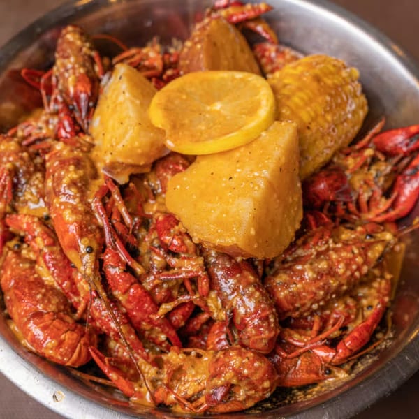 King Cajun Crawfish seafood boil with crawfish, potatoes, corn, and lemon slices in a metal bowl.