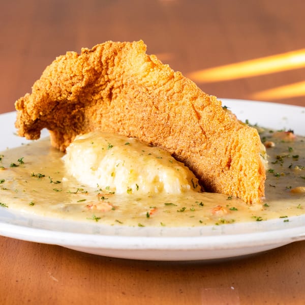 Crispy fried fish fillet and rice covered in a creamy Cajun crawfish étouffée sauce.