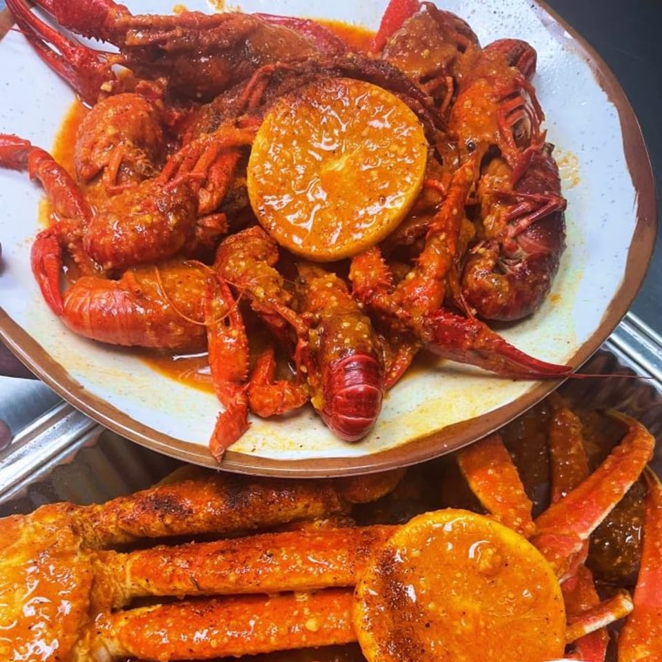 King Cajun Crawfish's spicy crawfish and crab legs with orange slices on a white plate.