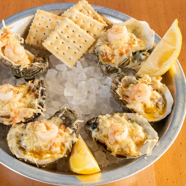 Baked oysters topped with shrimp and cheese, served on ice with crackers and lemon wedges.